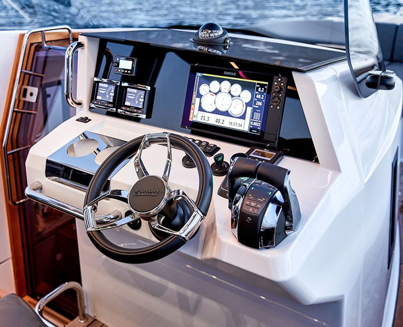 Primer plano de la zona de navegación y electrónica de un barco. Se ve el volante y todos los instrumentos de electrónica.